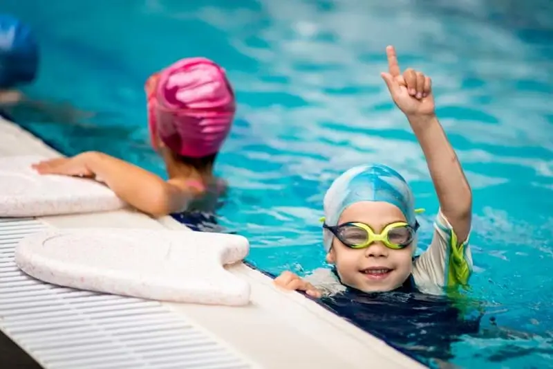 Child in swimming cap pointing to the ceiling