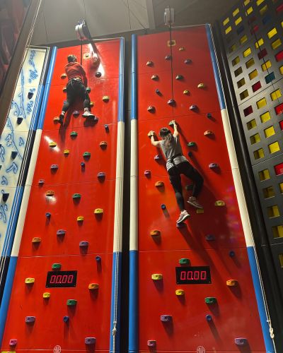 Two women climbing a Clip N Climb wall at Places Leisure