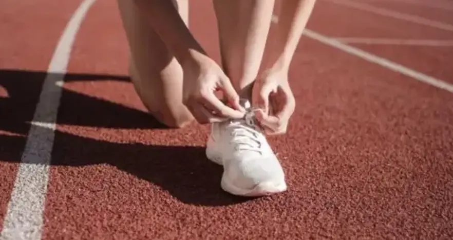 Runner tieing their laces on a running track