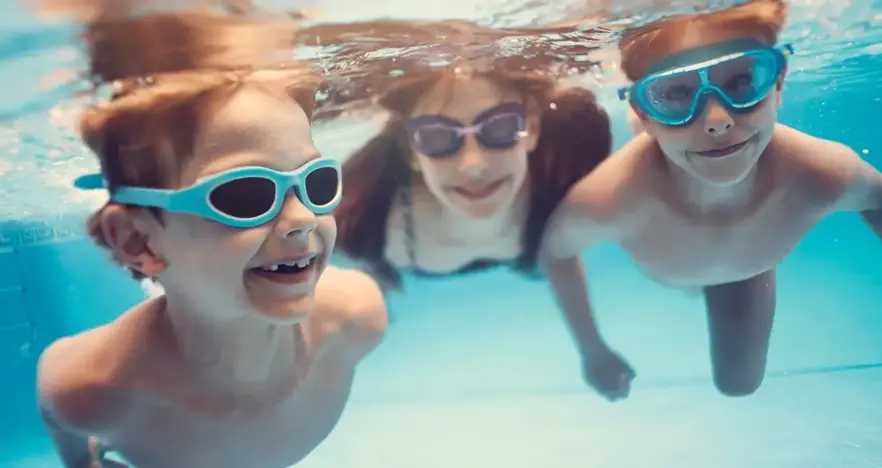 Two children and woman swimming while wearing goggles