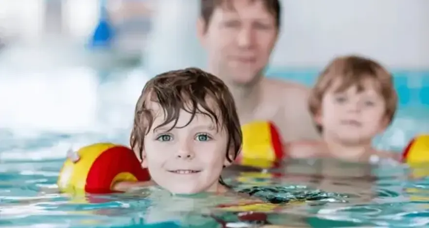 Man and two children swimming in arm bands