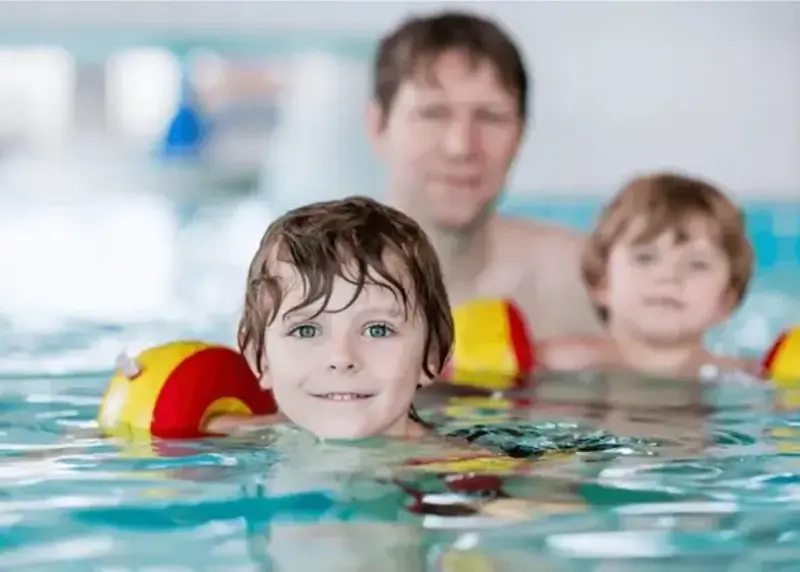 Man and two children swimming in arm bands
