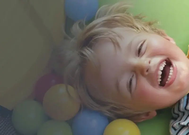 Child lying down in softplay with small balls around them