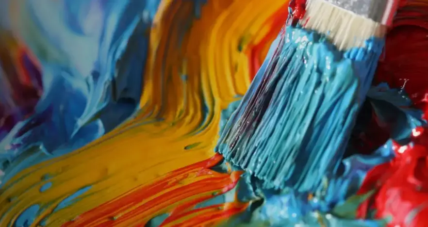 Close up of paint brush on multi-colour paint