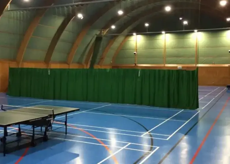 Table tennis tables in a sports hall with blue floor