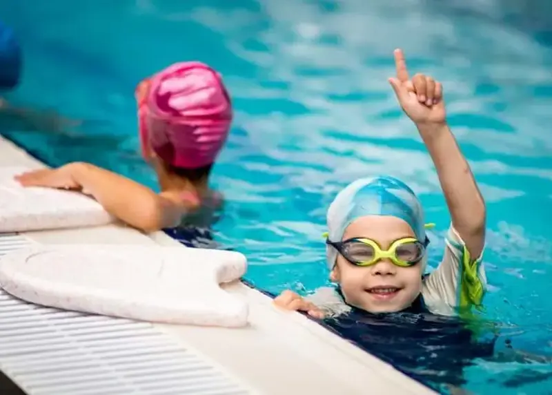 Child in swimming cap pointing to the ceiling